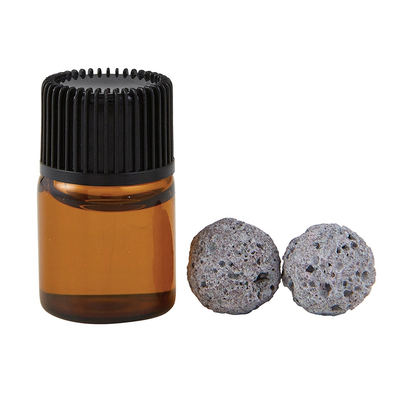 Amber glass bottle with black cap and two gray volcanic balls on a white background